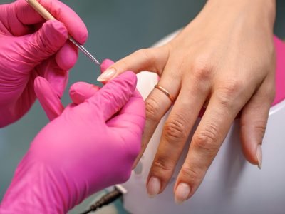 beautician applying Polish nails to woman nails. manicure process