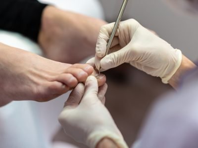 Closeup view of professional beautician wearing gloves making a pedicure.